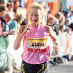 eine blonde Läuferin im rosafarbenen Oberteil mit Startnummer beim Dresden Frauenlauf.