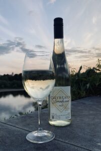 Speisen & Getränke auf der Dachterrasse: Ein Glas weißer Strandwein und eine Weinflasche während der blauen Stunde auf dem Citybeach Dresden