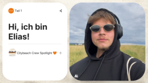 Porträt von Elias im Rahmen des „Citybeach Crew Spotlight“ mit schwarzem Hoodie, Kopfhörern und Sonnenbrille vor einer Naturkulisse.