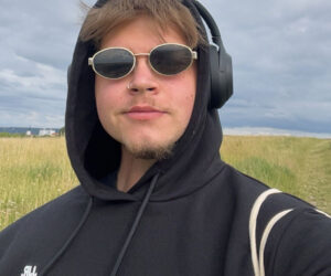 Das Bild zeigt den 23 jährigen Elias im Selbstportait mit Sonnenbrille und Overear-Kopfhörer